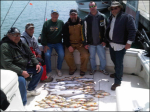 group of 6 on a boat with their fish