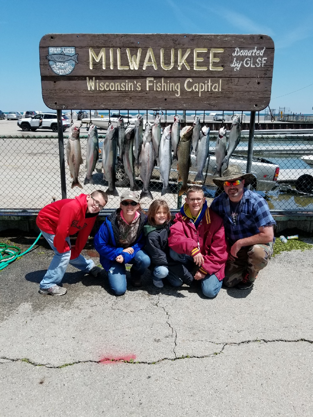 A group of six fishermen at Reel Sensation’s dock at Milwaukee Marina with a long lineup of large fish from Lake Michigan
